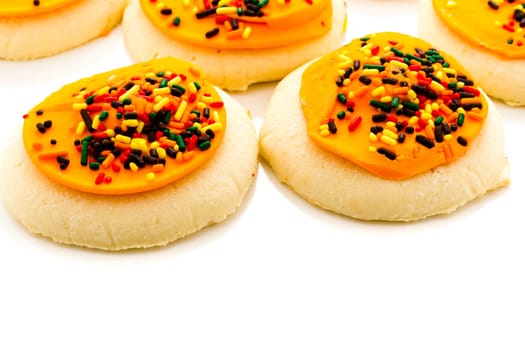 Sugar cookies with orange icing and spkinkles.