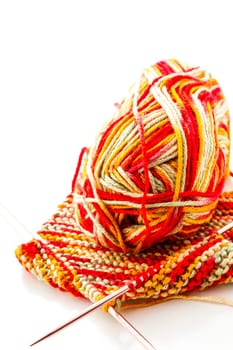 Knitting with multi colored yarn with orange, red, and yellow tones.