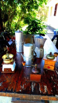Coffee machines and grinders on the table in the garden on a summer morning.