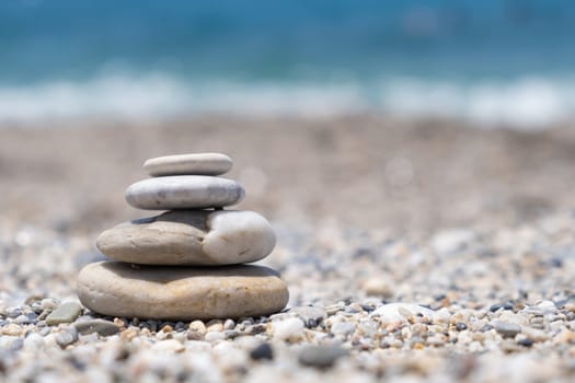 Round stones lie on top of each other in a column on the seashore on a sunny summer day. The concept of order and tranquility