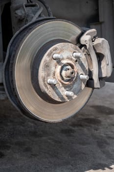 Disc brake of the vehicle for repair, in process of new tire replacement. Car brake repairing in garage. Replacement of brake pads. Suspension of car for maintenance brakes and shock absorber systems.