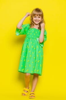 Young preteen child girl kid shouting, raising fists in gesture I did it, celebrating success, winning, birthday, lottery jackpot goal achievemen. Children isolated on yellow background. Vertical shot