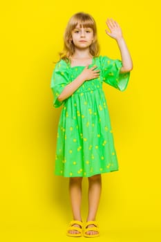 I swear to be honest. Sincere responsible child girl kid raising hand to take oath, promising to be honest tell truth be polite, keeping hand on chest. Preteen children on yellow background. Vertical