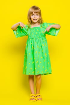 Young blonde child girl kid pointing with fingers at copy space below for advertising, like, subscribe, follow in social media app, recommend proposal announcement. Little preteen children. Vertical