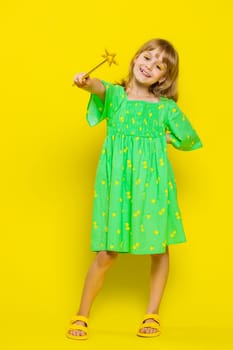 Magician school girl witch gesturing with magic wand fairy stick, making wish come true, casting magician spell, advertising holiday sale discount. Child kid isolated on yellow background. Vertical