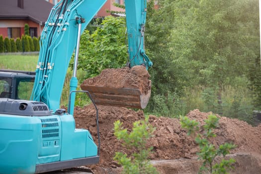 The process of working heavy construction equipment. A big blue excavator is pouring earth into a truck. Road works, reconstruction of the road surface. High quality photo