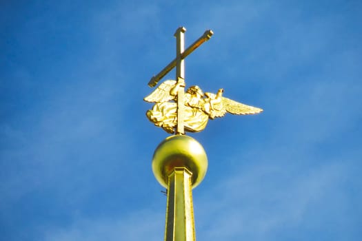 Golden angel and cross on the spire of the cathedral against the blue sky