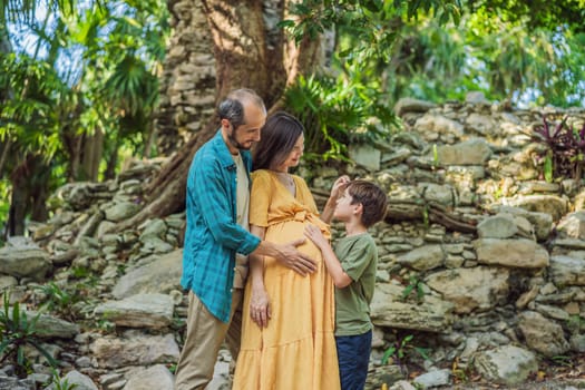 A loving family enjoying a leisurely walk in the park - a radiant pregnant woman after 40, embraced by her husband, and accompanied by their adult teenage son, savoring precious moments together amidst nature's beauty. Pregnancy after 40 concept.