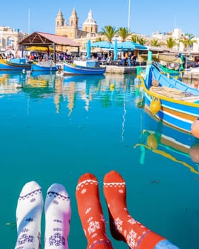 colorful Christmas socks and Maltese fishing boats at the harbor of the village Marsaxlokk Malta, Marsaxlokk harbor fishing boats colorful Malta on a sunny day in winter