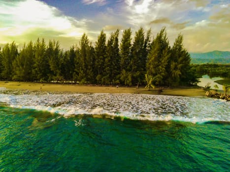the beautiful Bali Beach in Blangpidie, South West Aceh, Indonesia with blue ocean against the blue sky shot with aerial drone. Gree pine trees on the sandy beach against the sky.