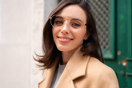 Streetstyle, street fashion concept: woman wearing trendy outfit walking in city. Cream trench coat, sunglasses