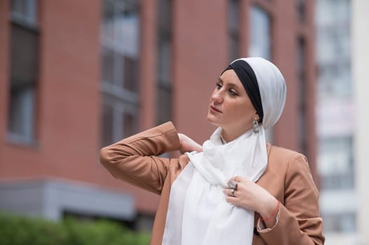 Young woman dressed in hijab and business suit walking outdoors