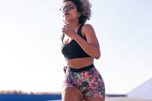 african american sportswoman running in a athletic track outdoors in a sunny day, concept of sport and active lifestyle, copy space for text