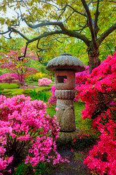 Stone lantern in Japanese garden with blooming flowers, Park Clingendael, The Hague, Netherlands