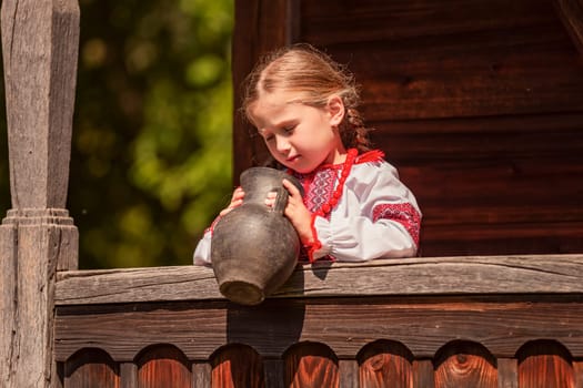 Girl in Ukrainian national dress with a jug outdoors