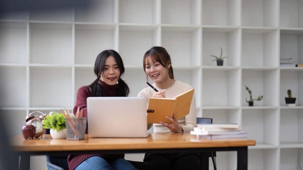 Two asian business discussing corporate strategy in teamwork, working on laptop in office at office.