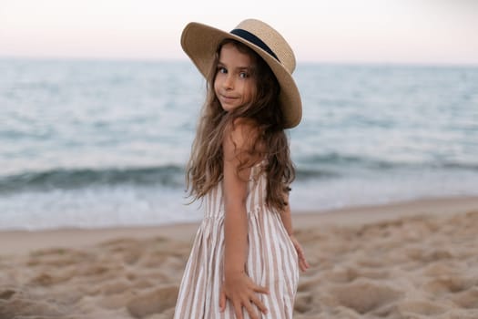 a baby girl in her sun hat on the beach.