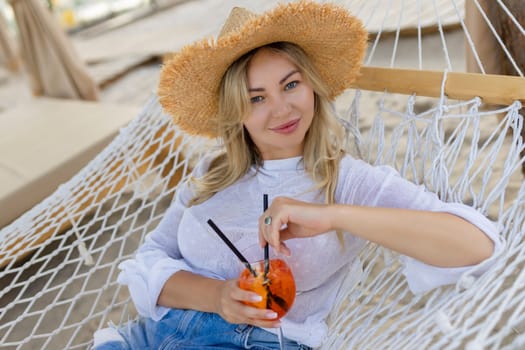 woman with cocktail relaxed in hammock.