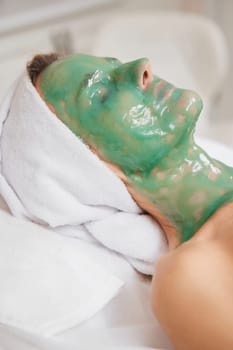 beautiful woman with green alginate mask on face in the spa salon. close-up