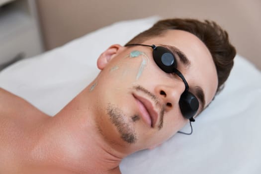 male face with gel before hair removal epilation in beauty center.