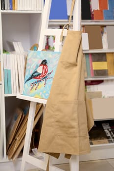 Still life. An oil painting is displayed on a white wooden easel with an apron in creative workshop. Hobby. Learning fine art painting