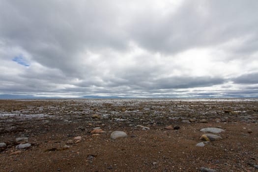 Arctic ocean shoreline at low tide exposing rocks, on a cloudy day, near Arviat, Nunavut Canada