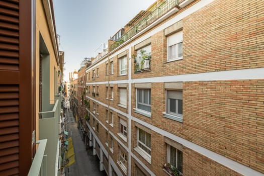 View from the balcony of a narrow barcelona street among modern brick houses. The concept of modern Spanish architecture. Tourist Europe.