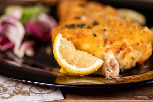 monkfish au gratin plate with composition on wooden top and wine glass and cutlery