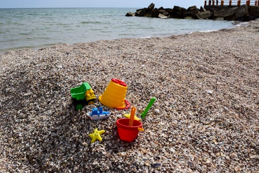 Child's bucket, spade and other toys on tropical beach against sea and blue sky.