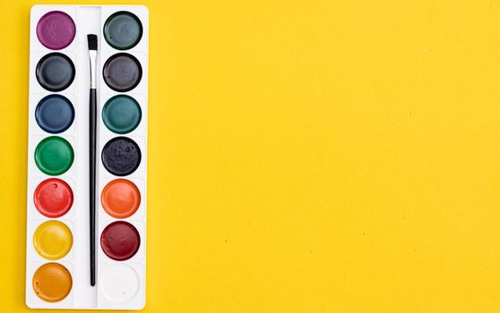 Watercolor paints on a yellow background . Paints for drawing. Hobbies and recreation. Office supplies. School supplies. Copy Space