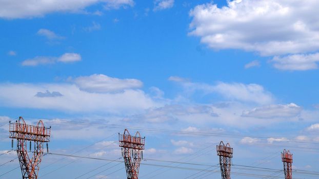 electric towers against the background of a clear sky with white clouds, copy space