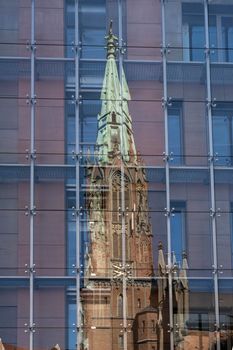 Riga, Latvia. August 2021. St. Gertrude Old Church reflected in the stained glass windows of a modern building in the city center