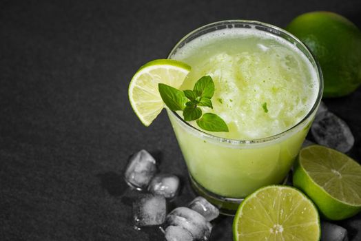 Cocktail juice with lime, mint and ice. Bar drink accessories on black table background.