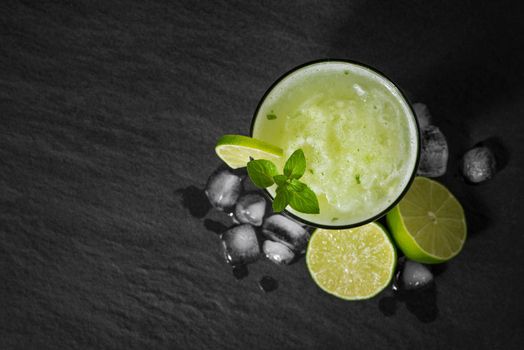 Cocktail juice with lime, mint and ice. Bar drink accessories on black table background.