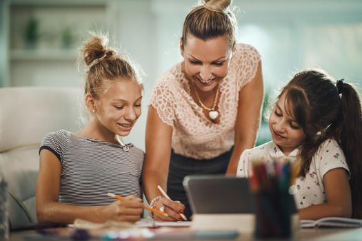 Shot of a beautiful young mother helping hers two daughters with homework during COVID-19 pandemic.