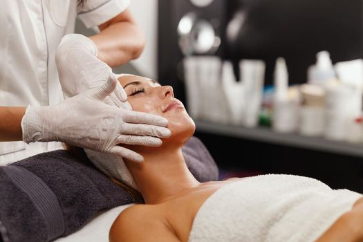 Shot of a beautiful young woman enjoying face massage at the beauty salon.