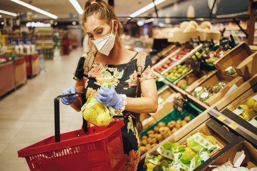 Shot of a young woman is wearing N95 protective mask while buying groceries in supermarket during Covid-19 pandemic.