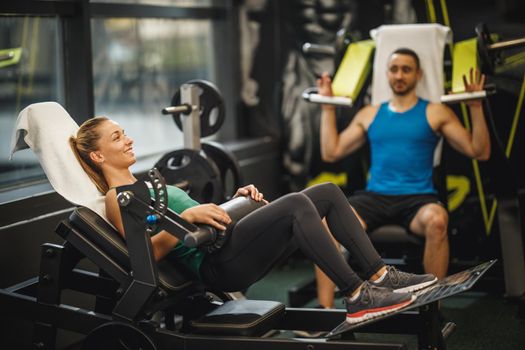 Shot of a muscular young woman in sportswear working out at the gym. She is doing glute bridge exercise for her gluteus on hip trust machine.