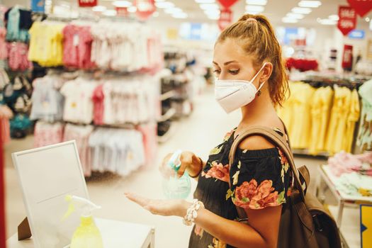 Shot of a young woman is wearing N95 protective mask and  using antiseptic spray to disinfect his hands while buying in supermarket during Covid-19 pandemic.