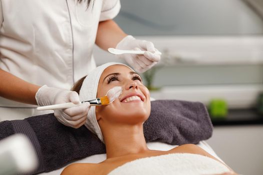 Shot of a beautiful young woman getting a facial mask treatment at the beauty salon.