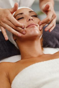 Shot of a beautiful young woman enjoying face massage at the beauty salon.