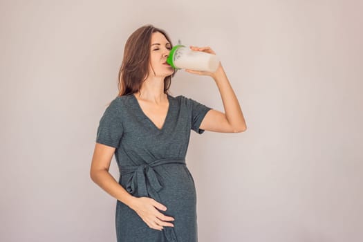 Energetic and fit pregnant woman after 40 enjoying a protein shake for a nourishing boost during her pregnancy journey. Embracing health and wellness for a thriving baby and mom.
