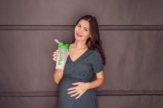 Mexico, Playa del Carmen 3.08.2023: Energetic and fit pregnant woman after 40 enjoying a protein shake iHerb for a nourishing boost during her pregnancy journey. Embracing health and wellness for a thriving baby and mom.