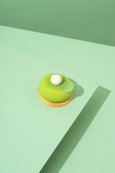 A freshly baked pastry with green and white icing, sitting atop a green-hued surface