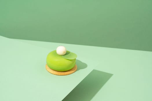 A freshly baked pastry with green and white icing, sitting atop a green-hued surface