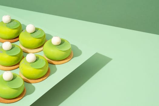A platter of assorted green donut treats sits atop a wooden table