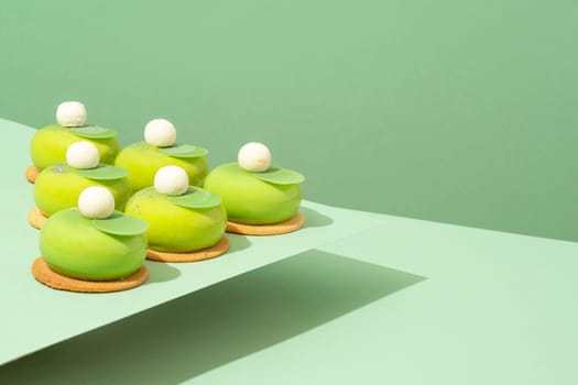 A platter of assorted green donut treats sits atop a wooden table