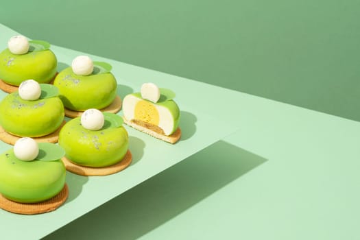 A platter of assorted green donut treats sits atop a wooden table