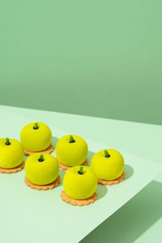 A platter of assorted green donut treats sits atop a wooden table