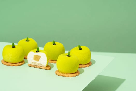 A platter of assorted green donut treats sits atop a wooden table